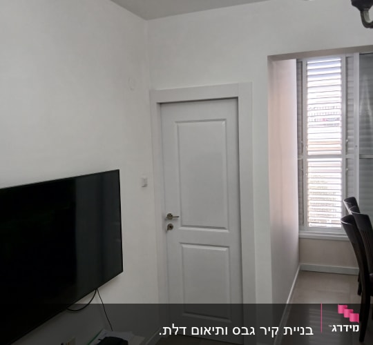 קיר גבס עם טלוויזיה תלויה ודלת לבנה